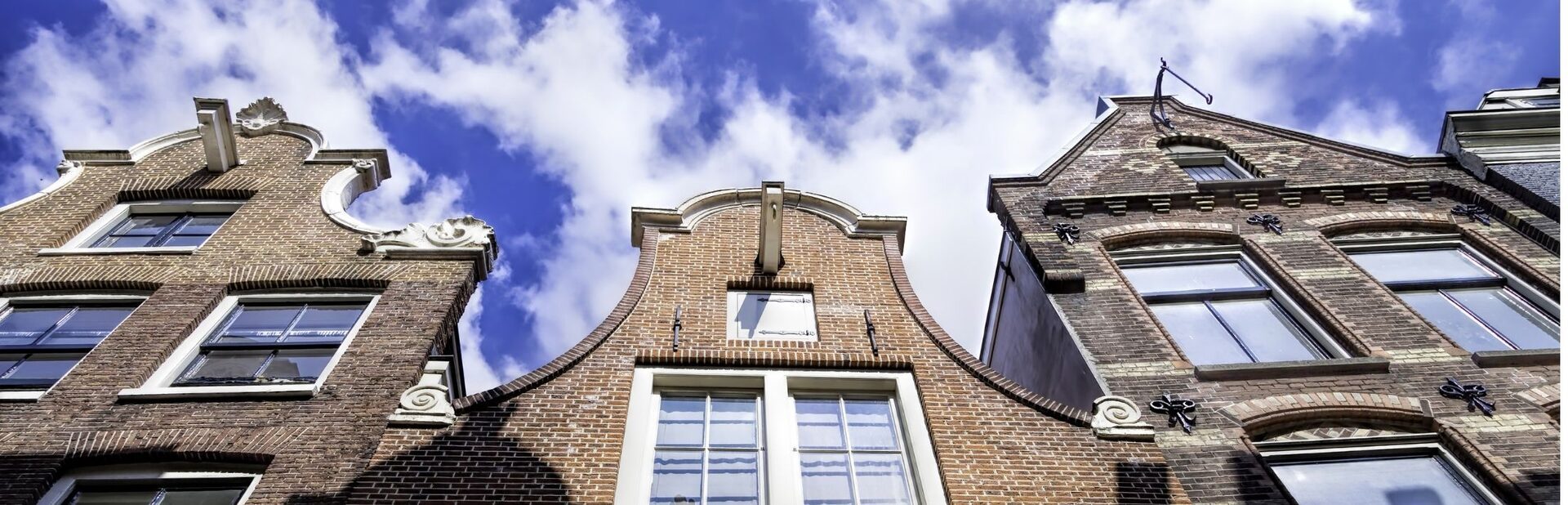 Rij Amsterdamse geveltoppen met hijsbalken onder de nok