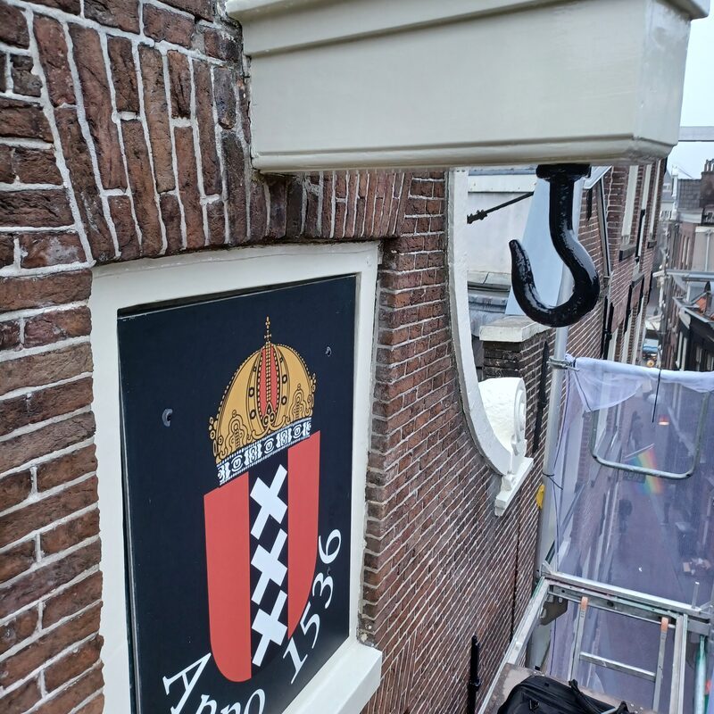 Beschilderd luik met het Amsterdamse wapen en het jaartal 1536, met daarnaast de hijshaak