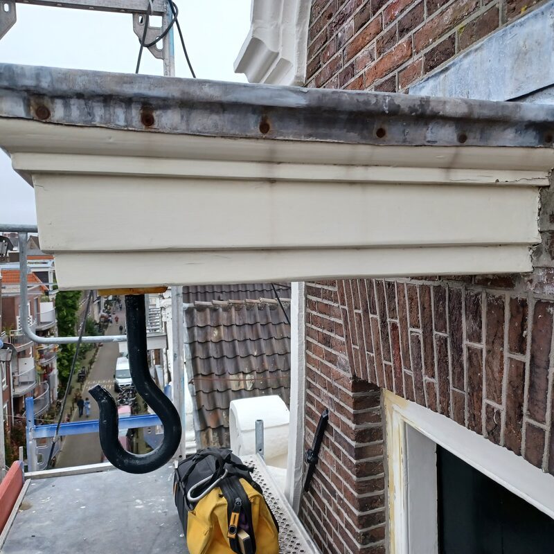 Houten hijsbalk met gesmede hijshaak aan een Amsterdamse gevel
